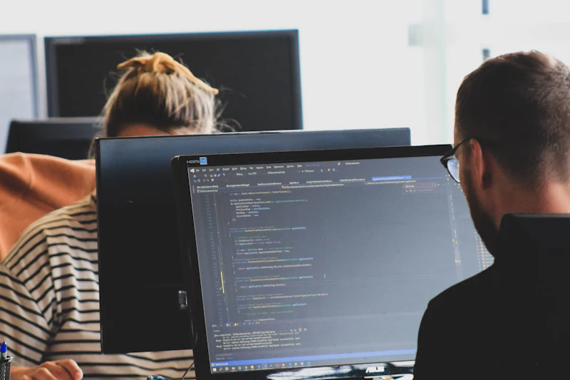 Twee ontwikkelaars werken aan code op grote schermen